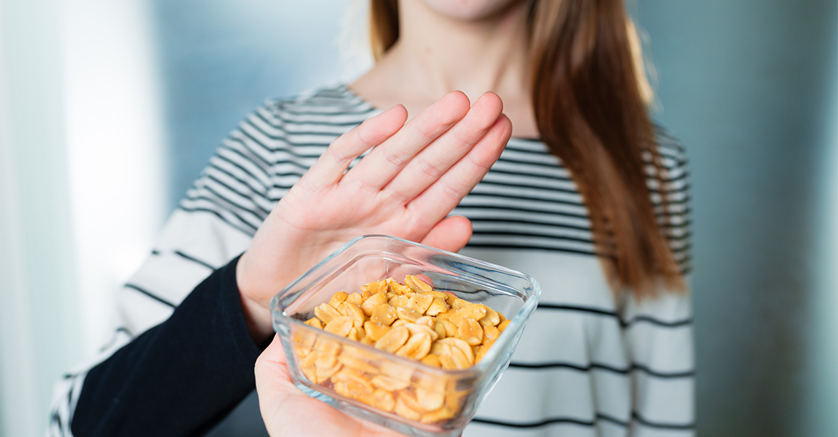 Holding hand up to a bowl of nuts due to food allergy