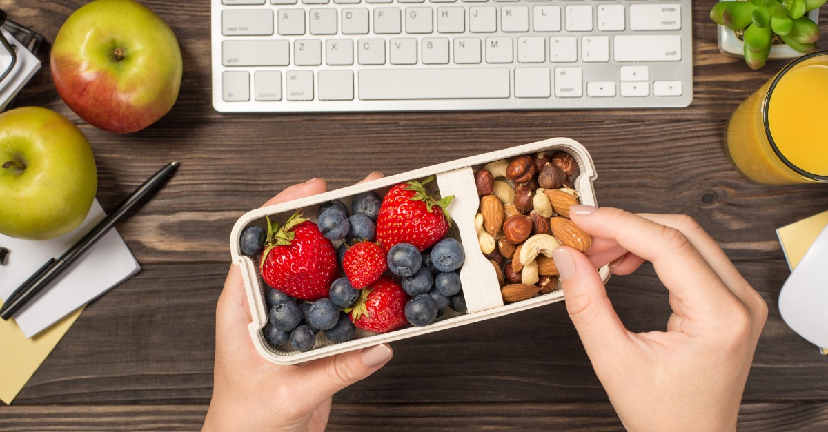 first-person-top-view-photo-of-womans-hands-holding-lunchbox-with-healthy-meal-nuts