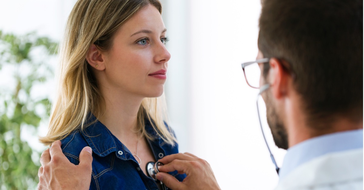 male doctor checking woman patient heartbeat