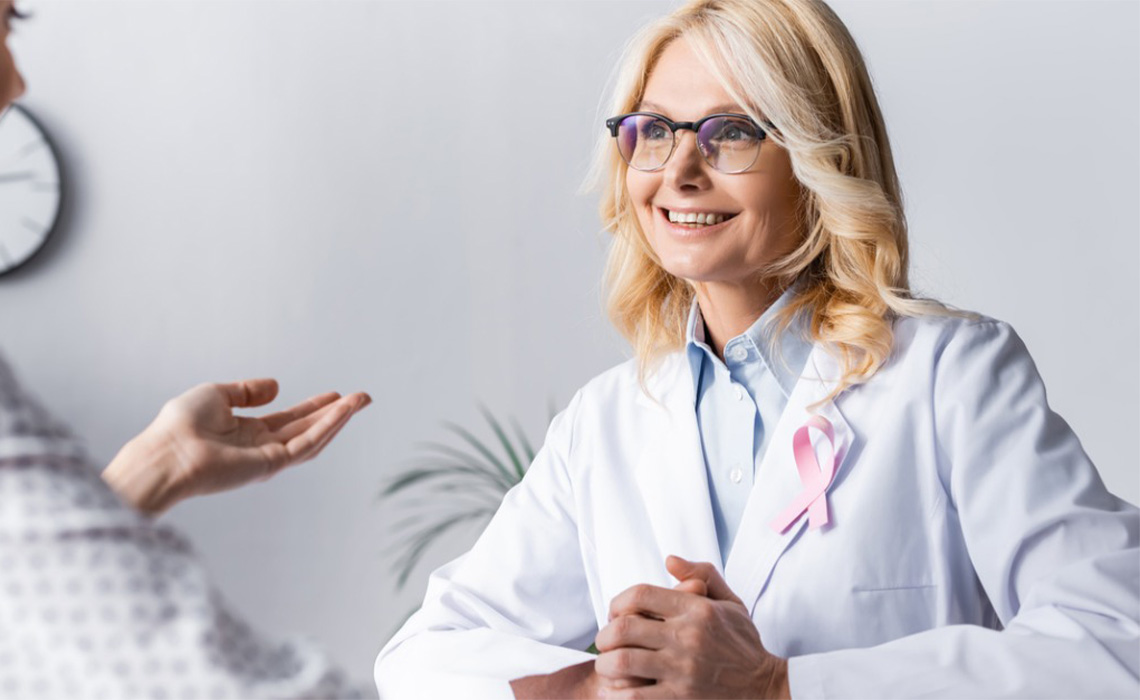 Breast cancer doctor smiling at patient in a doctor office setting.