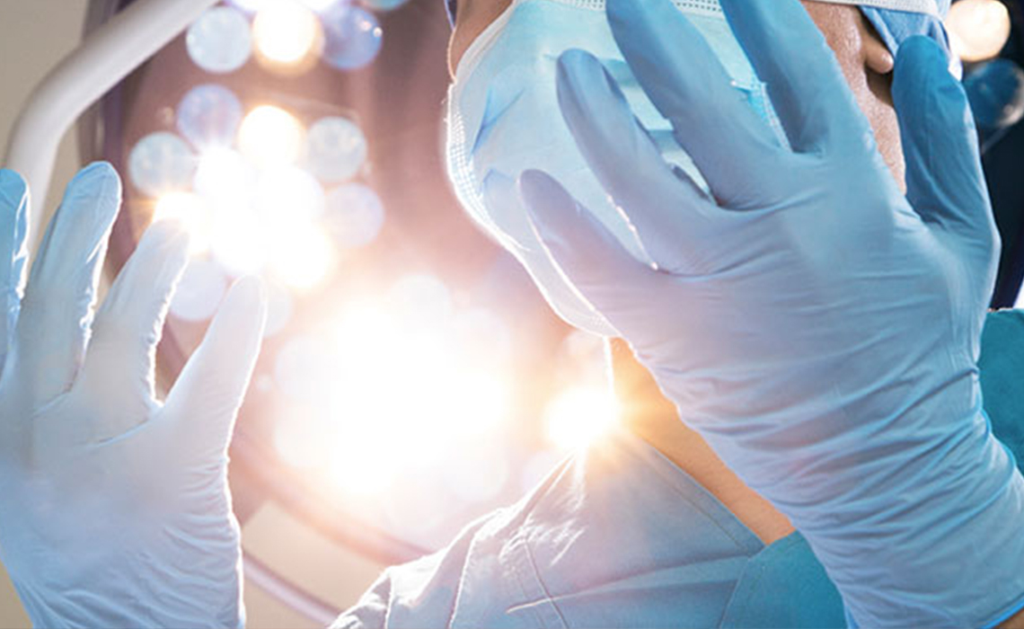 A proud surgeon looking down at their gloved hands.